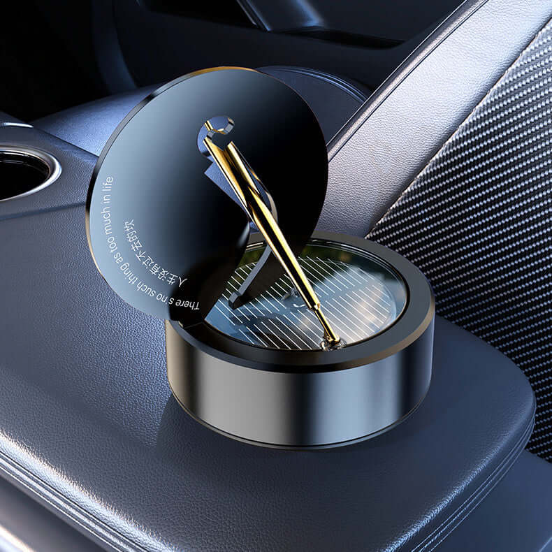 Solar rotating aromatherapy car air freshener in obsidian black with gold accents on a car console.