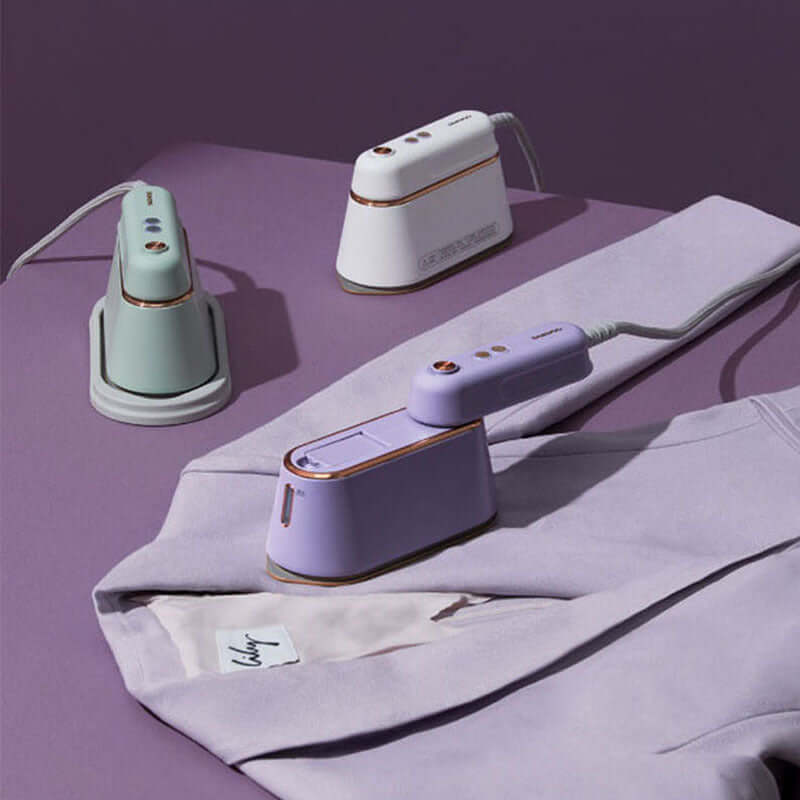 Portable handheld steam ironing device in toffee white, pod green, and gray lotus root purple on a garment.