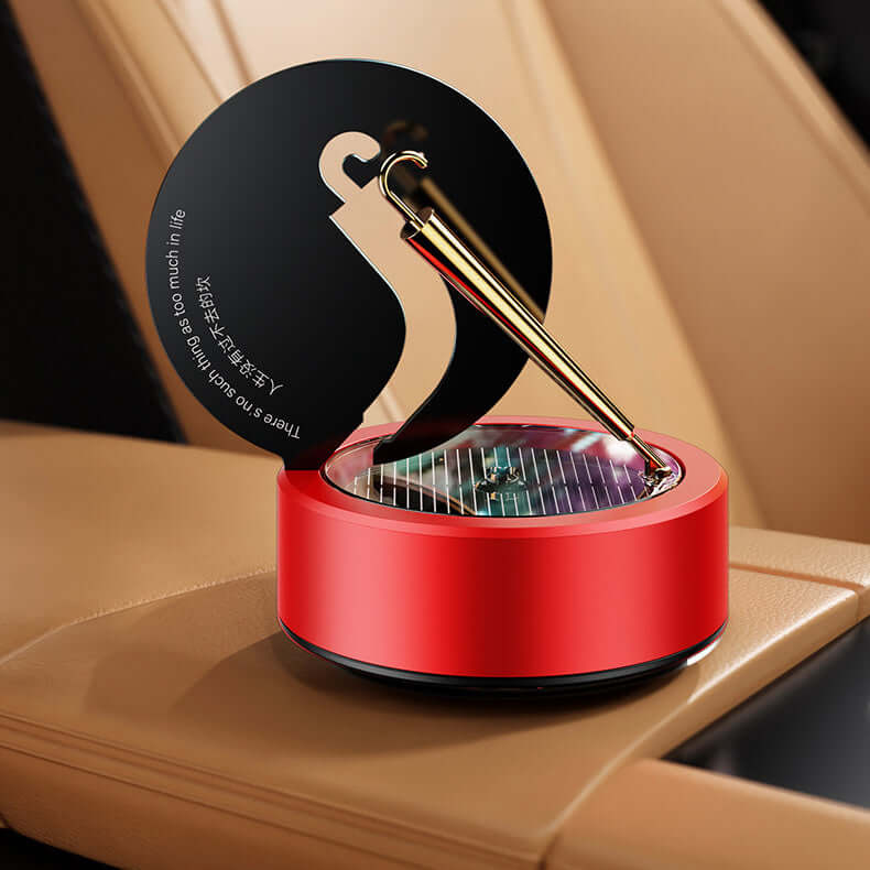 Red solar rotating aromatherapy car air freshener with essential oil holder, sitting in a car's cup holder.